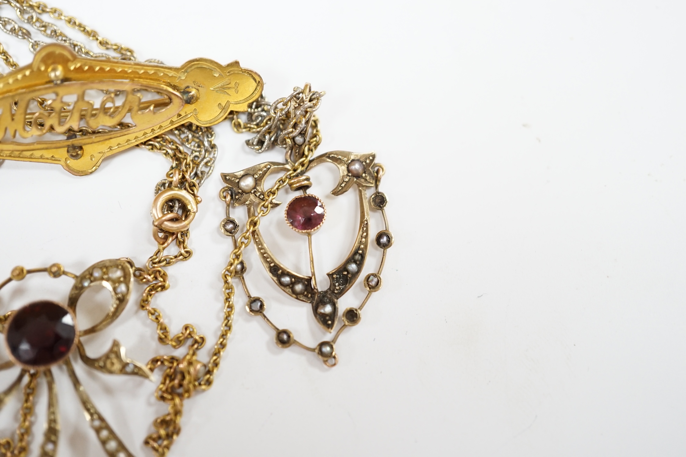 An early 20th century 9ct, garnet and seed pearl set pendant necklace, 43cm, one other similar 9ct and gem set pendant, on a gilt metal chain and a yellow 'metal 'mother' brooch. Condition - fair